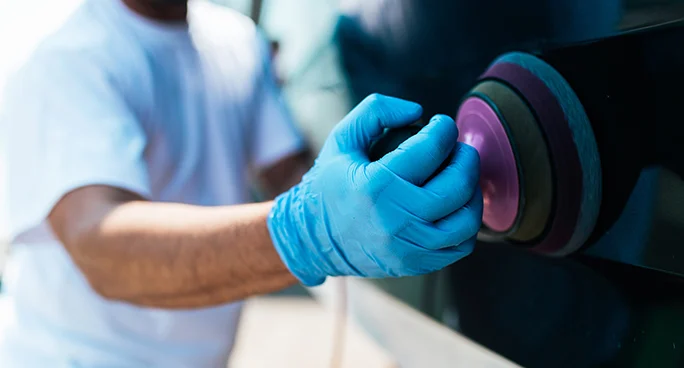 Technician polishing a boat hull with a buffer